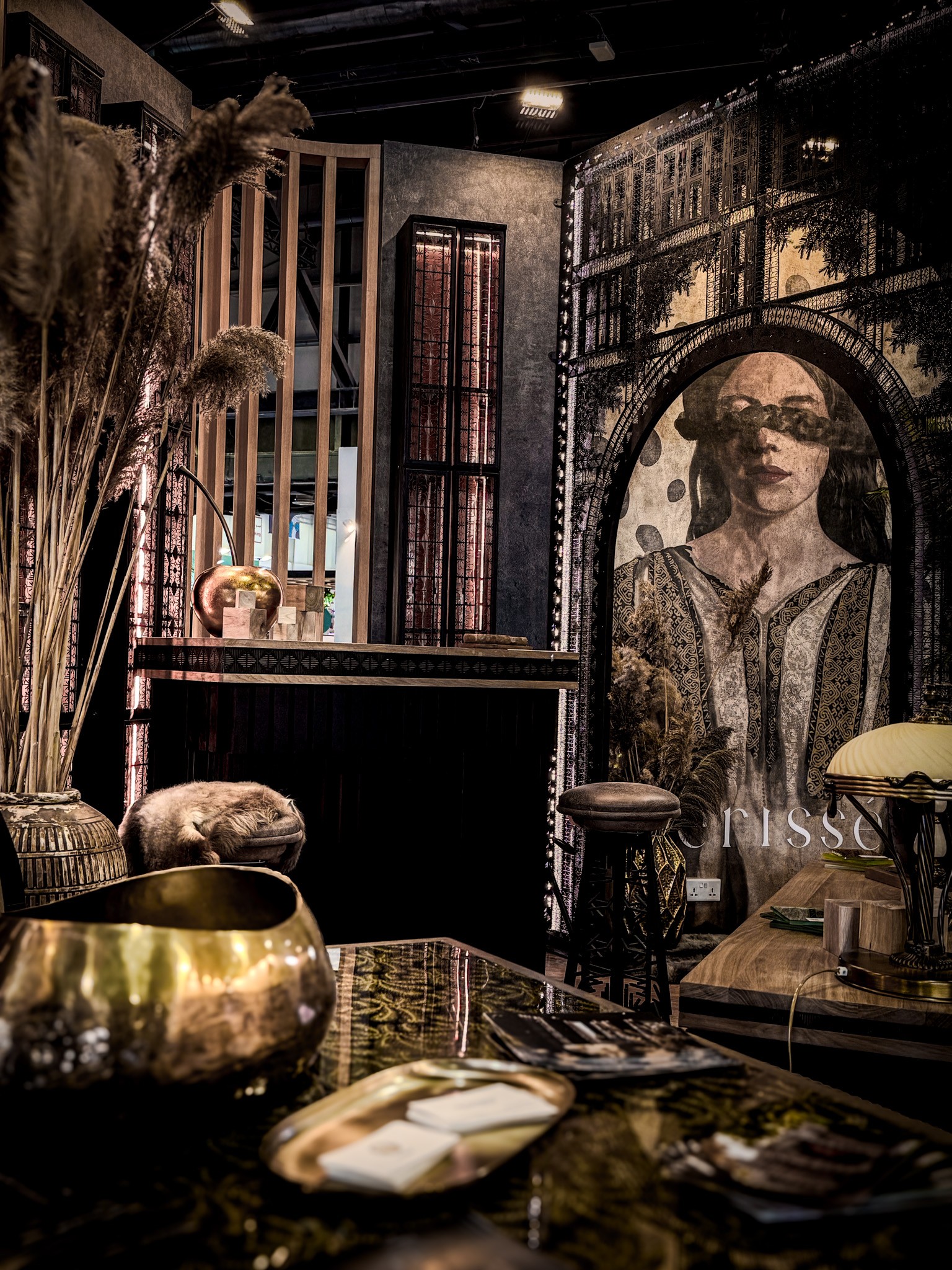 Moody bar interior with a dark counter, layered decorative screens, and a large mural portrait
